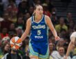 Paige Bueckers brings the ball up the floor in a blue Dallas Wings road uniform against the Seattle Storm at Climate Pledge Arena.