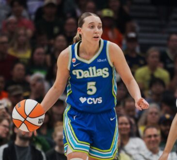 Paige Bueckers brings the ball up the floor in a blue Dallas Wings road uniform against the Seattle Storm at Climate Pledge Arena.