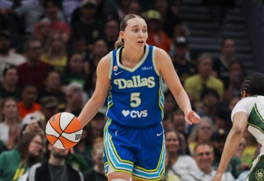 Paige Bueckers brings the ball up the floor in a blue Dallas Wings road uniform against the Seattle Storm at Climate Pledge Arena.