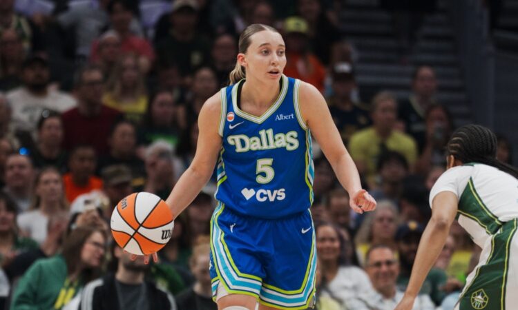 Paige Bueckers brings the ball up the floor in a blue Dallas Wings road uniform against the Seattle Storm at Climate Pledge Arena.