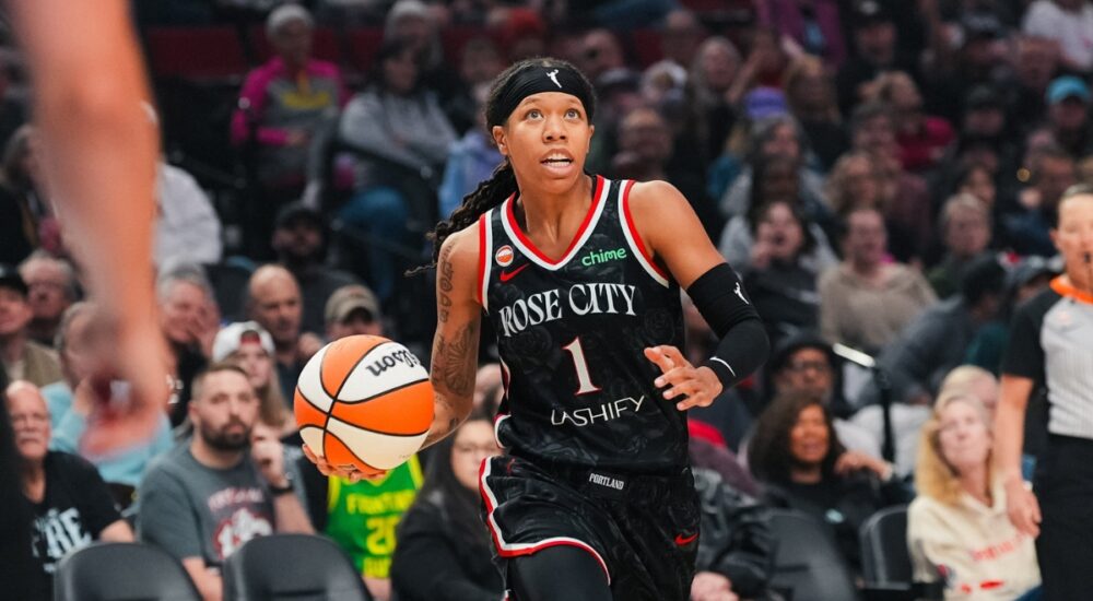 Sug Sutton dribbles up the court in a black Rose City Portland Fire jersey during a WNBA game