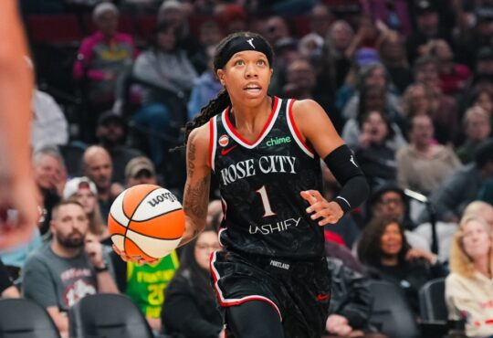 Sug Sutton dribbles up the court in a black Rose City Portland Fire jersey during a WNBA game