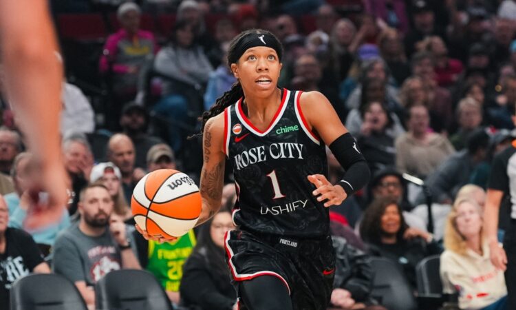 Sug Sutton dribbles up the court in a black Rose City Portland Fire jersey during a WNBA game