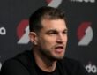 Tiago Splitter speaking at a Portland Trail Blazers press conference in front of a Moda and Trail Blazers logo backdrop