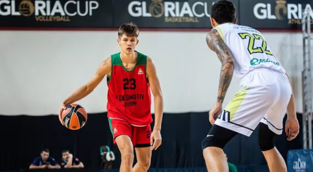 Vsevolod Ishchenko dribbles in a red and green Lokomotiv Kuban No. 23 jersey while a defender guards him during a game