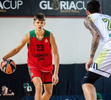 Vsevolod Ishchenko dribbles in a red and green Lokomotiv Kuban No. 23 jersey while a defender guards him during a game