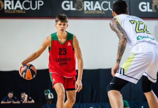 Vsevolod Ishchenko dribbles in a red and green Lokomotiv Kuban No. 23 jersey while a defender guards him during a game