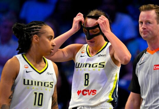 Alanna Smith of the Dallas Wings adjusts her protective mask after colliding with Gabriela Jaquez of the Chicago Sky during their WNBA game on June 20, 2026