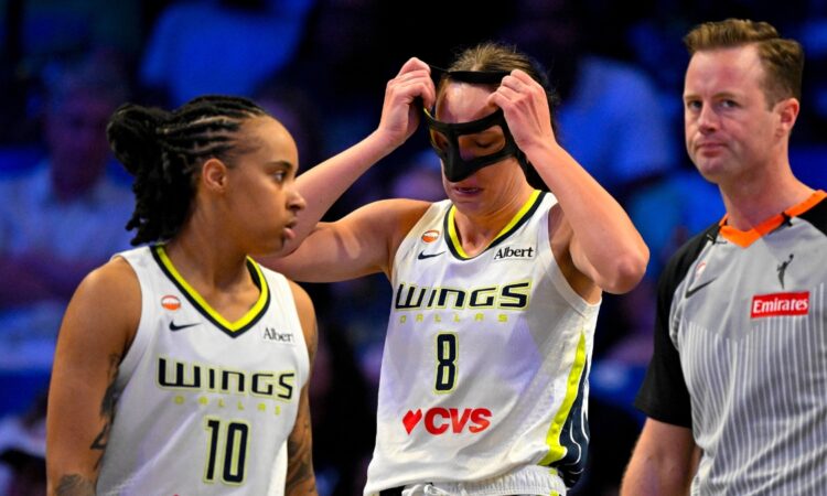 Alanna Smith of the Dallas Wings adjusts her protective mask after colliding with Gabriela Jaquez of the Chicago Sky during their WNBA game on June 20, 2026