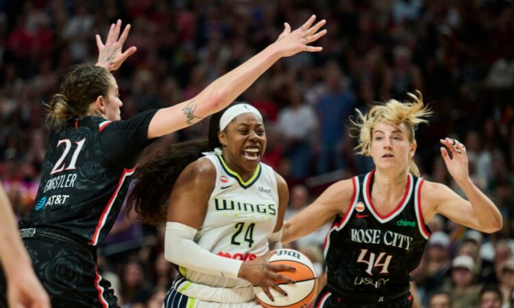 Dallas Wings guard Arike Ogunbowale drives to the basket between Portland Fire defenders Emily Engstler and Karlie Samuelson during the second half at Moda Center on July 22, 2026.