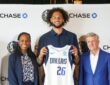 Dereck Lively II holds a Dallas Mavericks jersey with the Chase patch alongside Rick Welts and Pauline Saunders at the partnership announcement