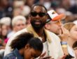 Dwyane Wade sits courtside in sunglasses and a cream jacket during the 2026 WNBA All-Star Game at United Center in Chicago.