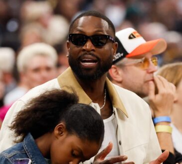 Dwyane Wade sits courtside in sunglasses and a cream jacket during the 2026 WNBA All-Star Game at United Center in Chicago.