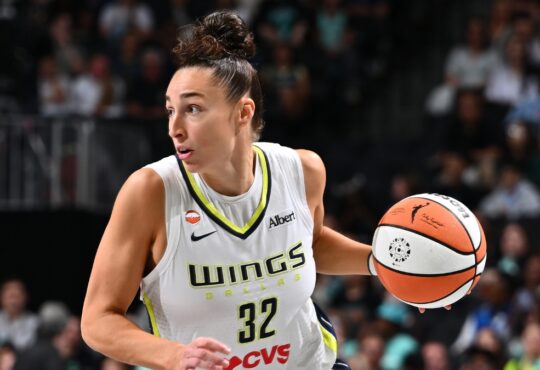 Dallas Wings forward Jessica Shepard dribbles the ball up the court in a white road jersey