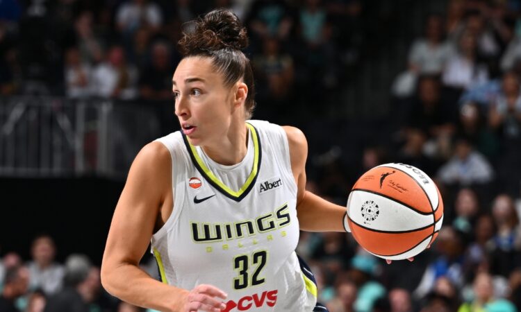 Dallas Wings forward Jessica Shepard dribbles the ball up the court in a white road jersey
