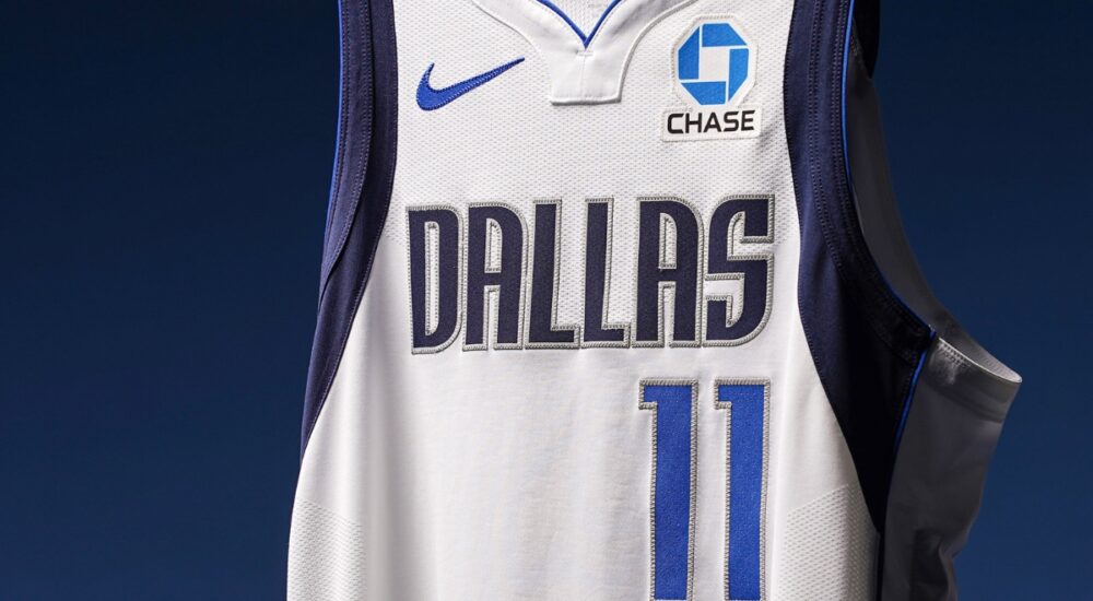 Close-up of a Dallas Mavericks white jersey showing the No. 11 and a new Chase logo patch on the left chest