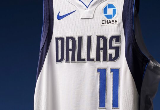 Close-up of a Dallas Mavericks white jersey showing the No. 11 and a new Chase logo patch on the left chest